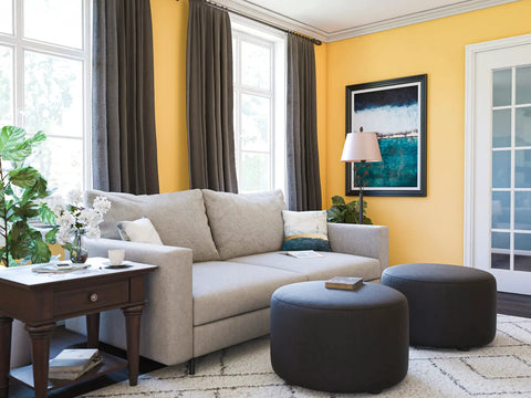 Living room with Rustic Oil Rubbed Bronze Floor Lamp With Leaf Finial And Gold Tapered Shade, cozy grey sofa, and dark ottomans.