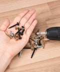 Hand holding various small screws and drill on wooden surface