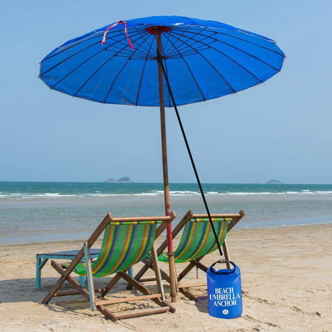 Two Pack Beach Umbrella Sand Weight Bags 10L 25LB Fillable Anchor Bags For Outdoor Wind Resistant Shade Setup Heavy Duty 500D PVC Includes Black Straps Easy Fill With Sand Stones Or Water 19.5 x 7 Inch anchoring a blue umbrella on the beach.