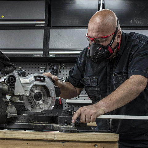 Person using a saw while wearing a Dust Mask With Replaceable Twin HEPA Filters For Woodworking And Construction, Half Face Pro Grade Mask