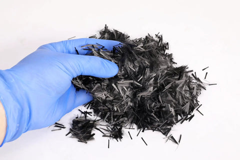 Gloved hand holding Quarter-Inch Chopped Carbon Fiber Strands, 4 Oz Jar For Resin Composites And Vacuum Bagging
