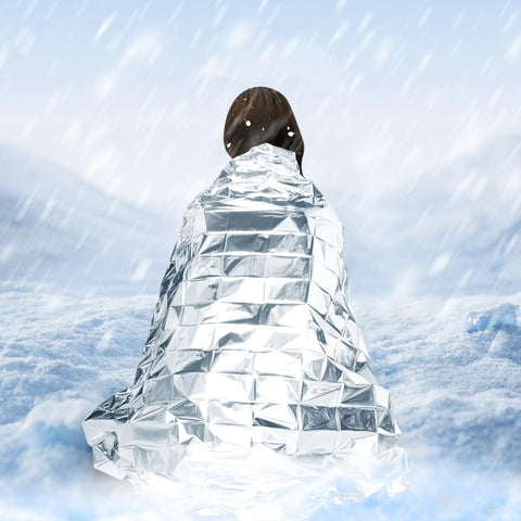 Person wrapped in Mylar Emergency Blankets Space Blanket Thermal Survival Gear in snowy outdoors.