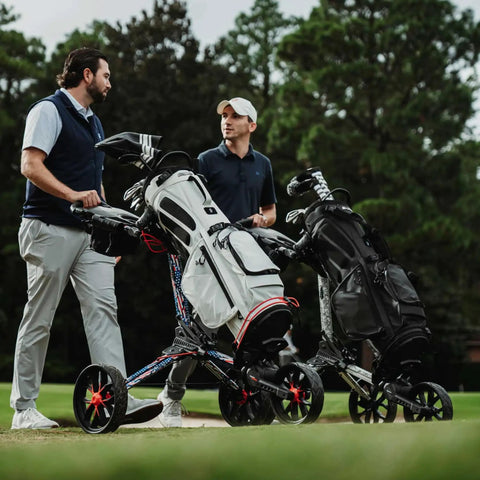 Two men conversing on golf course next to Nitron Golf Push Cart With Auto Open Technology and Top Lok System in black and slate finish.