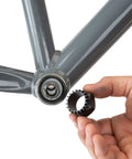 Hand holding Bottom Bracket Tool BBT-32 for 20-Tooth Splined Cups Shimano and Drive near bicycle frame
