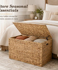 Handwoven Water Hyacinth Storage Trunk With Lid And Handles by a bed, used for storing blankets, natural finish, boho farmhouse decor