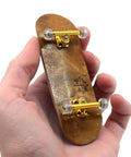 Hand holding 32mm Pro Fingerboard Complete Set with Pro Shaped Wooden Deck 32x97mm, UltraSpin Bearing Wheels, ready to ride.