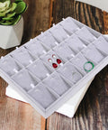 Large Grey Velvet Jewelry Tray With 18 Grid Dividers For Necklace And Watch Storage Soft Lined Organizer Dish on wooden surface with jewelry in compartments.