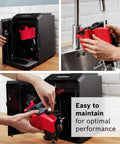 Fully Automatic Espresso Machine With Milk Frother System And Touch Control Panel Plus Cup Warmer For One Touch Latte and Cappuccino Maker In Sleek Dark Silver being cleaned at a sink.