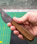 Person holding a Round Leather Knife For Cutting, Trimming, Skiving And Shaping Pro Grade High Carbon Steel Blade With Comfortable Wooden Handle Durable Leatherworking Tool For DIY Projects over a green cutting mat