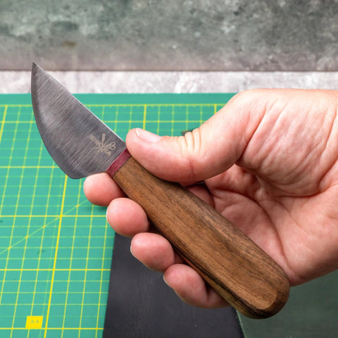 Person holding a Round Leather Knife For Cutting, Trimming, Skiving And Shaping Pro Grade High Carbon Steel Blade With Comfortable Wooden Handle Durable Leatherworking Tool For DIY Projects over a green cutting mat
