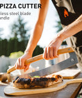 Person using Pi Pizza Rocker Cutter Pro For Effortless Slicing Of Thin Or Thick Crust Pizza With Stainless Steel Rocker Blade And Bamboo Handles