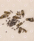 20 Pieces Jewelry Box Latches Set Thickened Solid Bronze Tone Antique Style Box Latch With Zinc Alloy Construction Includes 80 Replacement Screws Right Latch Buckle For Secure Elegant Storage displayed on fabric surface.