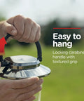 Hands holding battery powered camping lantern with 550 lumens, 360 degree light, carabiner handle shown outdoors.
