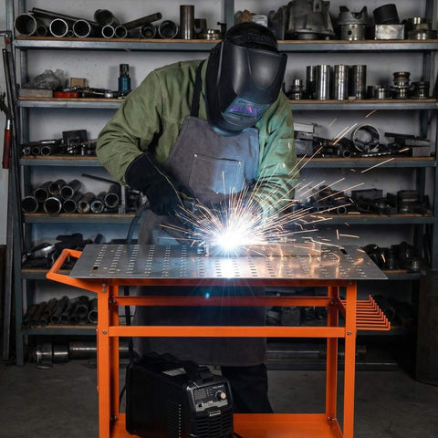 Worker using Rugged 36 Inch By 24 Inch Welding Table With 800 Pound Capacity Portable Welding Workbench On Wheels in garage workshop