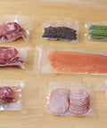 Top Notch Vacuum Sealer Bags 11 In x 50 Ft Sous Vide Roll 2 Pack with various foods sealed to prevent freezer burn
