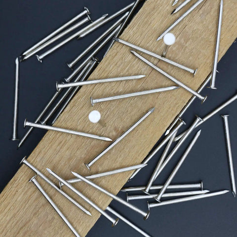 Zero Drama 120 Pack Of 2 Inch Nickel Plated Rust Proof Carbon Steel Hardware Nails scattered on wood.