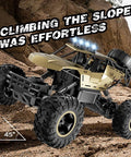 Rugged 1:12 Scale RC Monster Truck With Durable Metal Body climbing a rocky slope, LED headlights on, all-terrain tires gripping terrain.