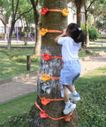 Child climbing a tree using Kids Outdoor Ninja Climbing Holds Set With 18 Rock Grips And 6 Ratchet Straps For Backyard Tree Obstacle Course Training