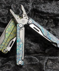 Camouflage Titanium Multitool Pliers Built Beefy With 420 Stainless Plier Head And 440 Steel Accessories on rocky surface
