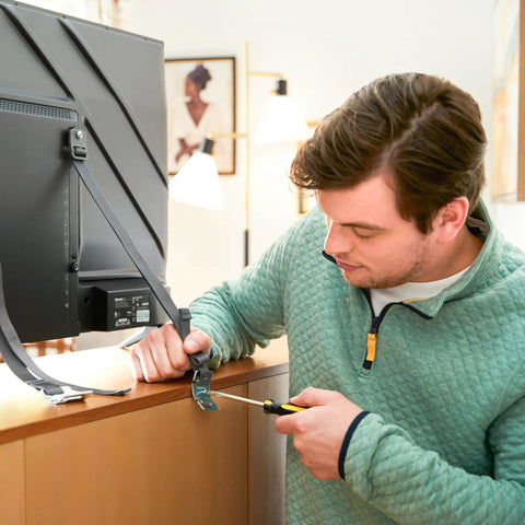 Man installing Universal TV Security Straps Four Pack For Wall Furniture And Anti Tip Configurations Secure Your TV To The Wall Or Furniture