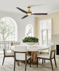 56" Soft Brass Chandelier Ceiling Fan,2 Downrods Fandelier with Remote above a modern dining table with solid wood base.