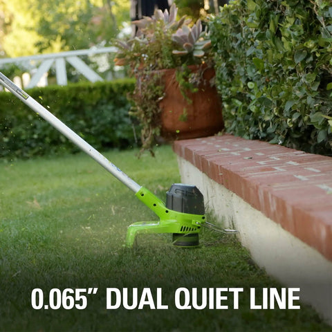 Side view of 40V Cordless String Trimmer with 12 Inch Cutting Path trimming grass along a brick edge in a garden setting.