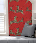 Wall with Red Zebra Safari Peel And Stick Wallpaper, featuring zebras and arrows, beside a window and gray cushions.