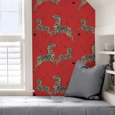 Wall with Red Zebra Safari Peel And Stick Wallpaper, featuring zebras and arrows, beside a window and gray cushions.