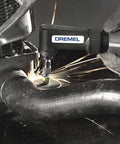 Dremel 575 right-angle attachment on a rotary tool grinding a metal pipe with sparks.