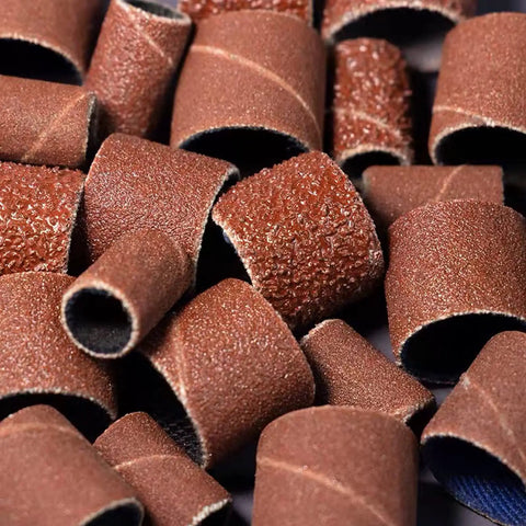Close-up of 320 Grit Sanding Bands Set With 100 Pieces And Two One Quarter Inch Mandrels For Rotary Tool Drum Sander Kit, 8Mm Diameter Circles, 12Mm Band Height, scattered view.