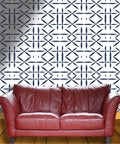 Snag This Top Tier Light Color Wallpaper Roll Boasting Thick Textured Vinyl Peel And Stick Design For Instant Room Glow Up And Chill Vibes Across Every Wall In Your Spot, featuring a geometric pattern behind a red leather couch.