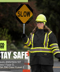 High Visibility Lightweight Waterproof Safety Rain Suit Featuring Reflective Work Jacket And Heavy Duty Bib Pants To Keep You Straight Up Dry At The Site, worn by traffic worker with sign.