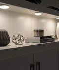Battery Operated LED Puck Light For Under Cabinets And Shelves With Motion Sensor And Auto Shut Off After 20 Seconds 30 Lumen Bright White Cabinet Lighting No Fuss Easy Install illuminating a shelf with decorative items
