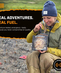 Woman in outdoor gear holding Hearty Beef Stroganoff Freeze Dried Backpacking Meal Just Add Water Made With Real Meat.