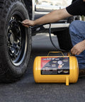Person using Grab And Go 5 Gallon Portable Air Tank With Sturdy Carry Handle to inflate vehicle tire with a quick connect chuck hose.