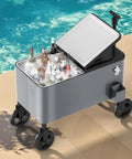 80 Quart Outdoor Rolling Ice Chest Wagon Cooler Cart With XL Wheels For Beach Patio And Parties Long Handle Beverage Cooler On Wheels For Easy Transport shown by a poolside, filled with ice and beverages, black and gray design.