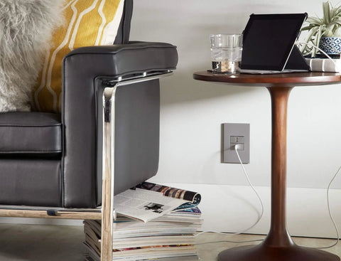 Living room with Adorne 1 Gang Wall Plate Magnesium Six Pack Screwless Snap In Design installed, shown near a table and chair.