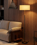 Two Light Floor Lamp With White Fabric Shade, Mid Century Tall Standing Lamp For Living Room And Bedroom, showing warm light setting, next to a sofa.