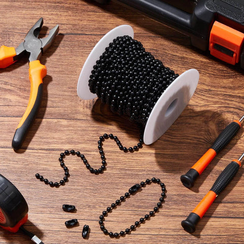 Black 50ft beaded chain for roller shades and vertical blinds with 50 connectors on spool, surrounded by tools on wood surface.