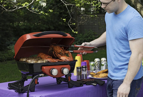 Man grilling lobsters using Stainless Steel 3 Piece BBQ Grilling Tool Set With Spatula Fork And Tongs Plus Bonus Grill Glove