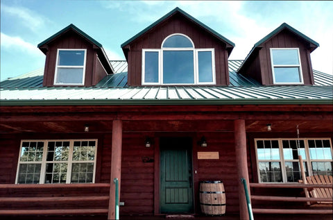 Log home exterior featuring premium one coat wood stain sealer in Black Canyon Red, showcasing windows and green door.