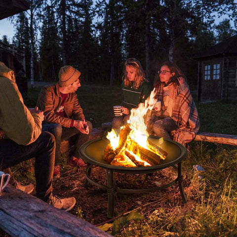 Group enjoying a 26 Inch Outdoor Wood Burning Fire Pit Heavy Duty Steel Bonfire Bowl With Spark Screen and Log Grate at night.