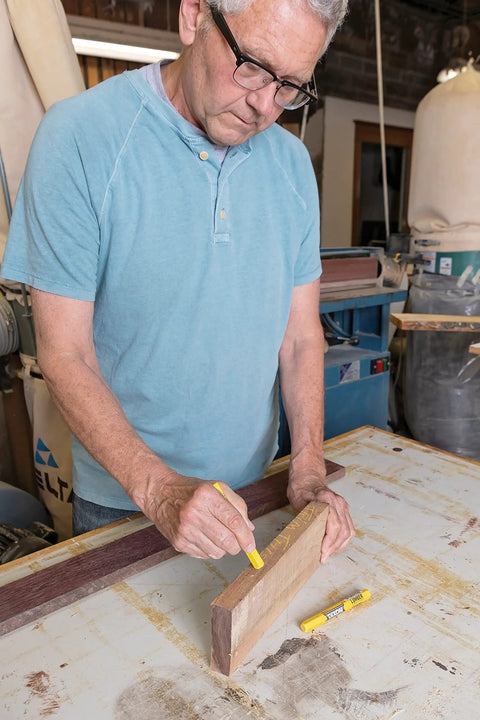 Man using Yellow Lumber Marking Crayons Hex Shaped 4.5 Inch By 0.5 Inch 12 Pack for woodworking in a workshop