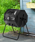 Dual Chamber Outdoor Compost Tumbler 42 Gallon with Sliding Doors and Gloves, black rotating bin next to a shed