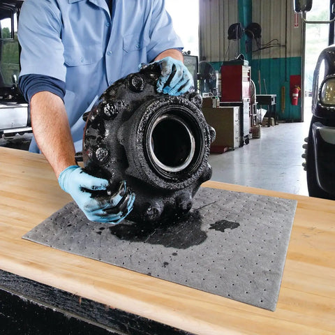 Mechanic using Premium Oil Absorbent Mat Pads 15 x 20 Inches, Heavy Duty 28 Oz Absorbency, for spill cleanup in workshop