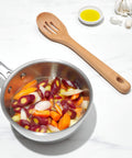 Wooden slotted spoon next to pan of vegetables, part of Three Piece Wooden Utensil Set With Solid Beachwood Spoon Slotted Spoon And Turner For Everyday Cooking No Fuss Kitchen Tools Built To Stir Lift And Serve Like A Pro