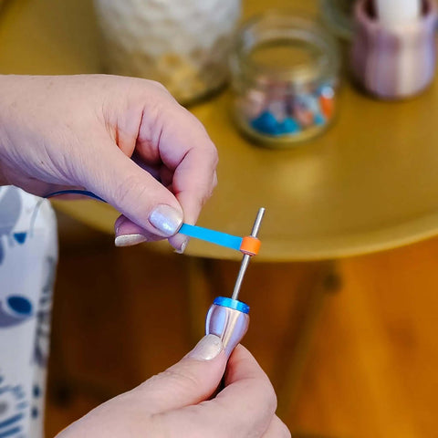 Close-up of hands using Two Piece Bead Roller Quilling Tool Kit With Slotted Winding Pins showing pink pearl silk handle.