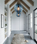 CASAMOTION Modern Farmhouse Blue Glass Globe Pendant Light 11" Dia. hanging in a well-lit hallway with rustic decor.