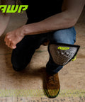 Person wearing Gel Pro Flooring Knee Pads With Dual Layer Gel And Foam Padding For All Day Comfort, kneeling on wooden floor, AWP logo visible.