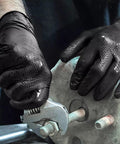 Close-up of black nitrile mechanic gloves with raised diamond texture gripping a wrench on a metal bolt